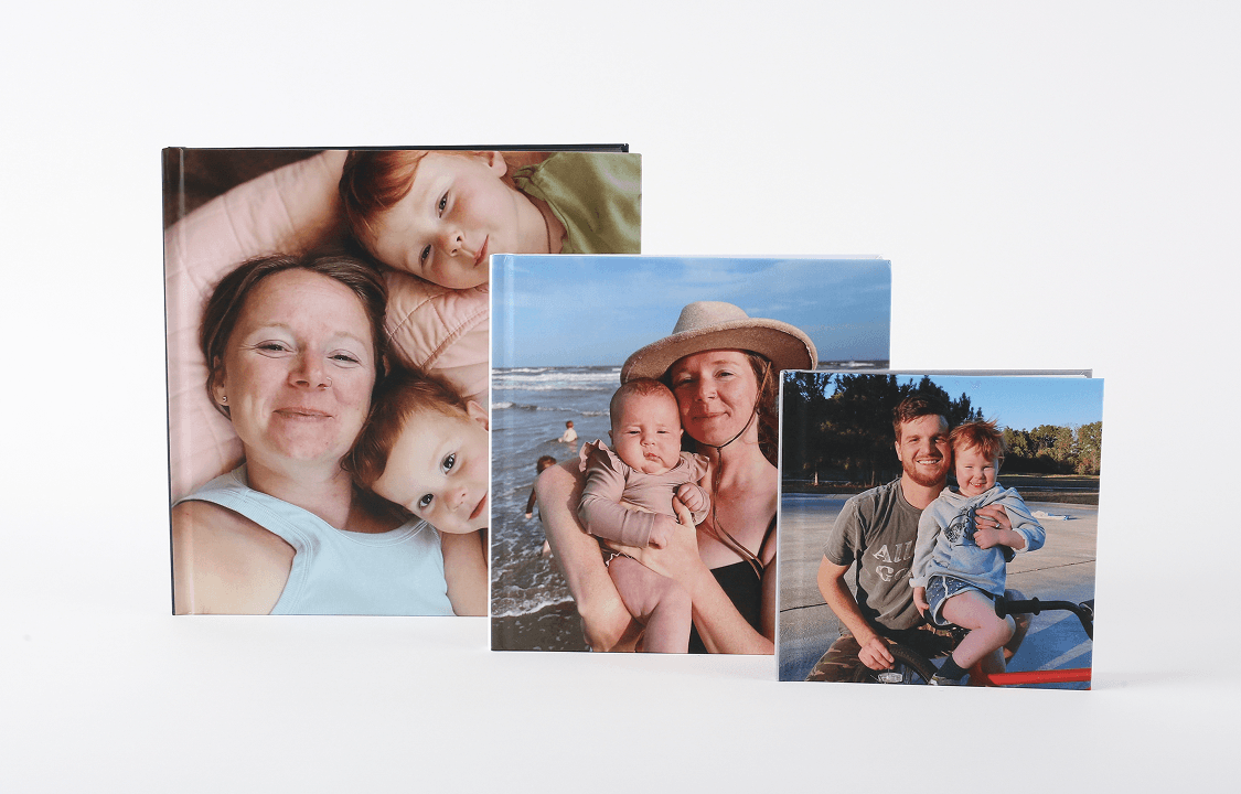 Four photo books displayed, each featuring unique colors and designs, showcasing a variety of styles and themes.