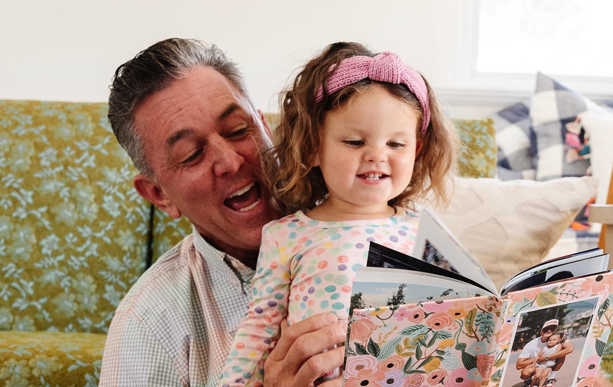 A collection of hardcover and softcover photo books arranged in a stack and standing upright, showing customizable covers and spine designs.