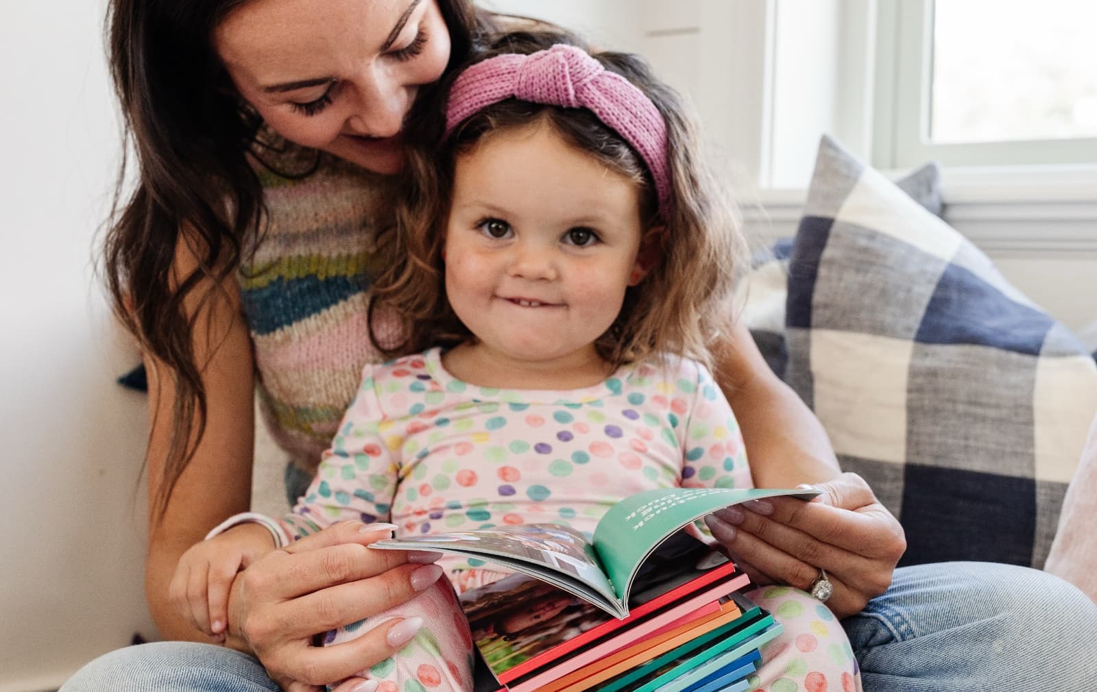 Mom and daughter sharing a laugh over a photo book.