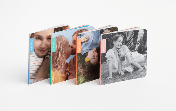 Four photo books displayed, each featuring unique colors and designs, showcasing a variety of styles and themes.