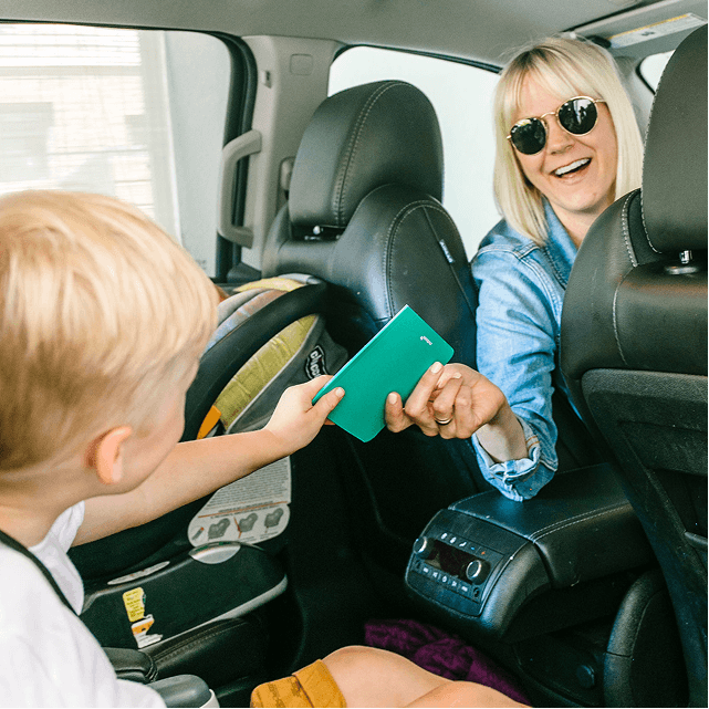 Toddler in a car seat holding a Monthly Mini photo book