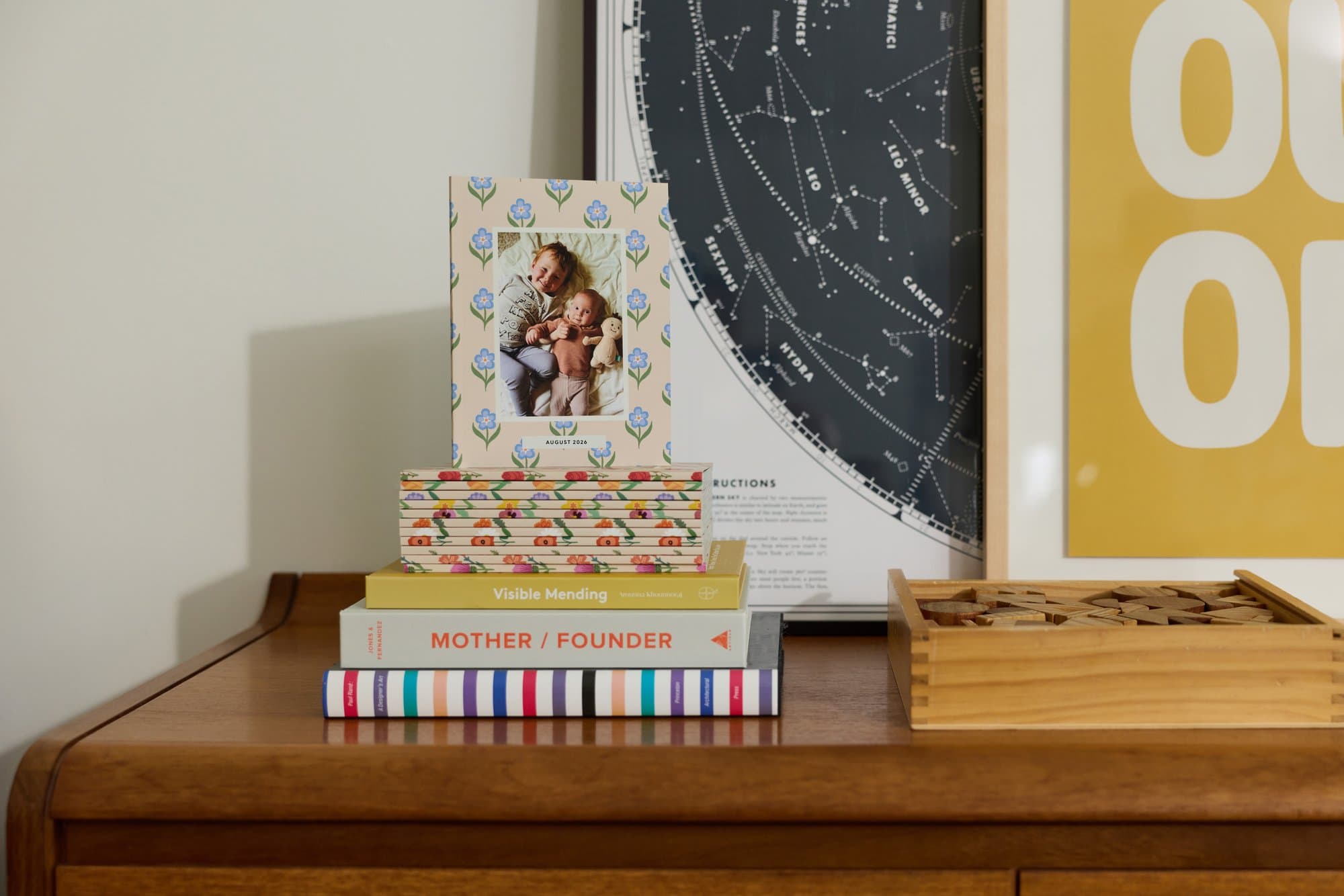 A Monthbook and a stack of design books styled on a wooden dresser