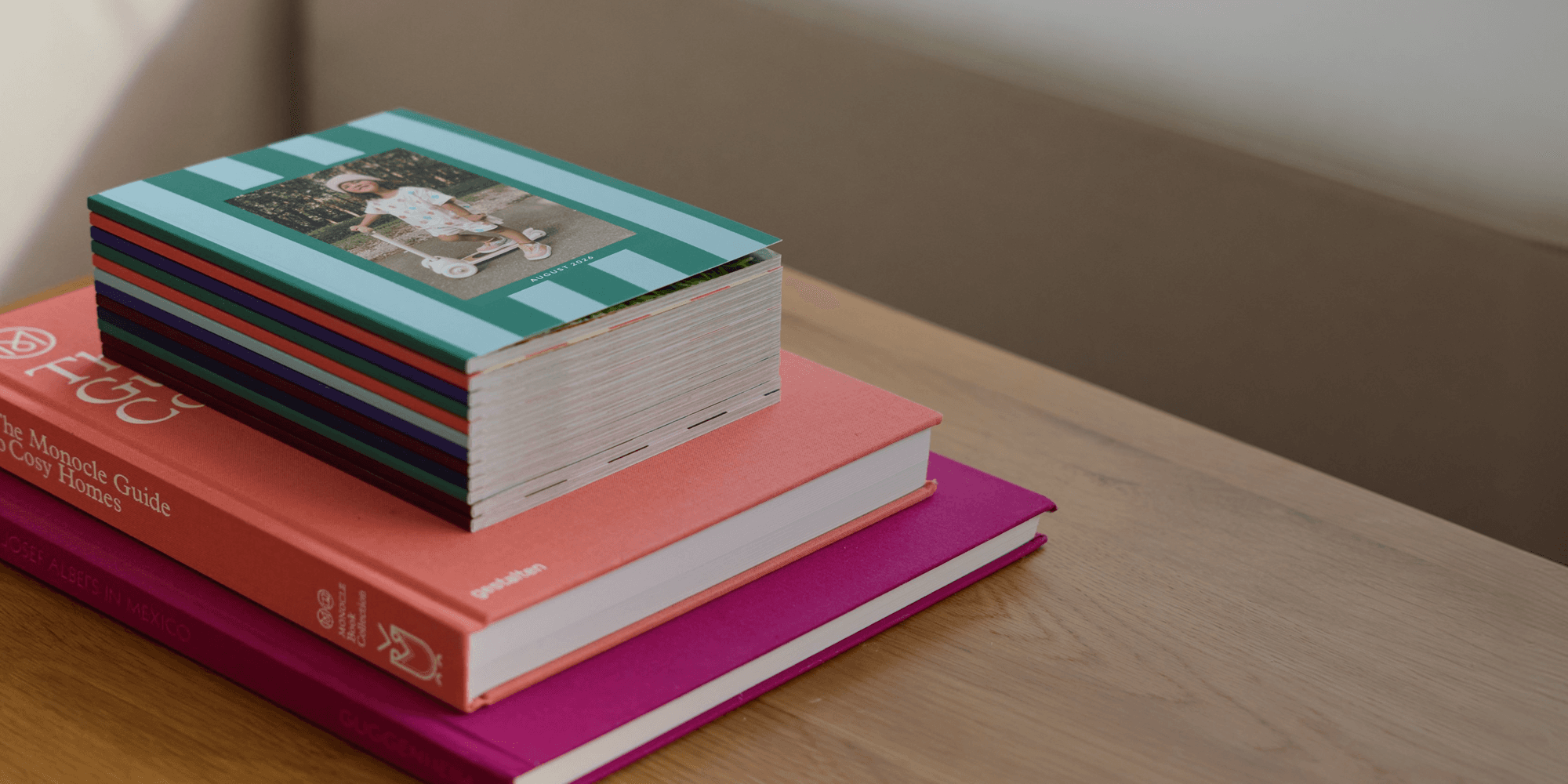 Stack of Chatbooks Monthbooks on a wooden table with coffee table books