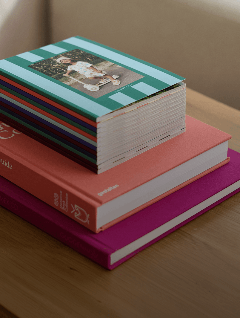 Stack of Chatbooks Monthbooks on a wooden table with coffee table books