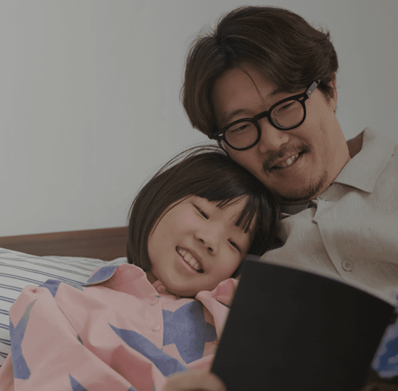 Father and daughter reading a Monthbook together in bed