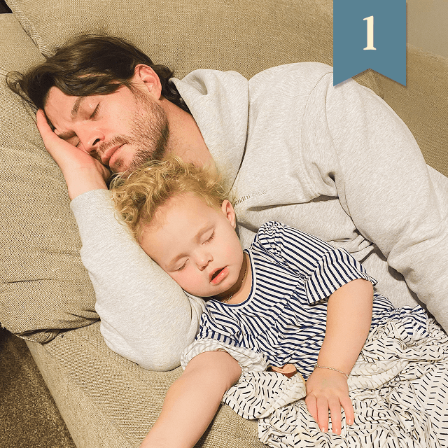 Dad and toddler napping together on a couch