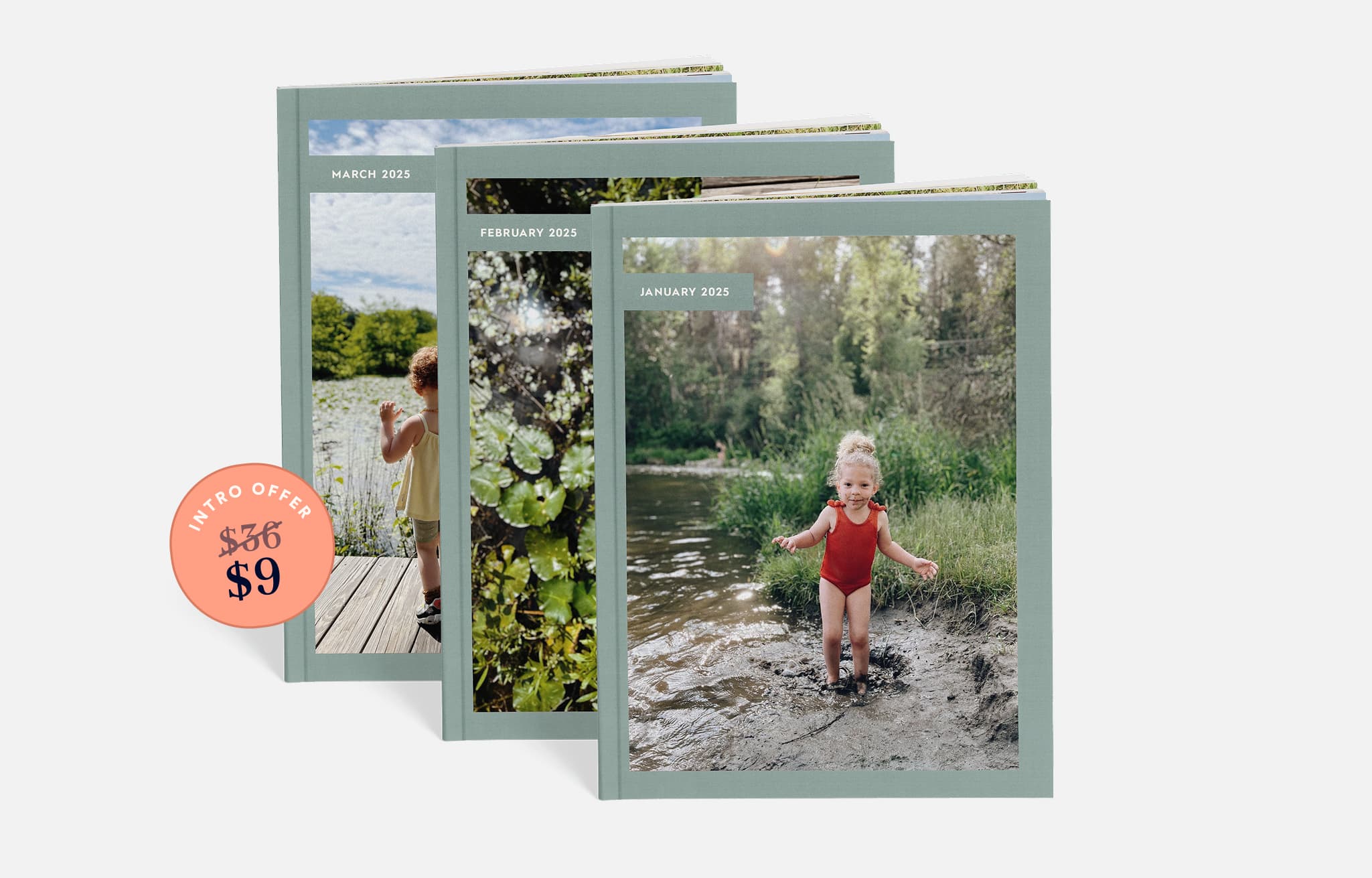 A stack of photo books stands upright, with the front book displaying a baby in a sun hat sitting on grass next to a dog in a red hat, both in front of a wooden fence.